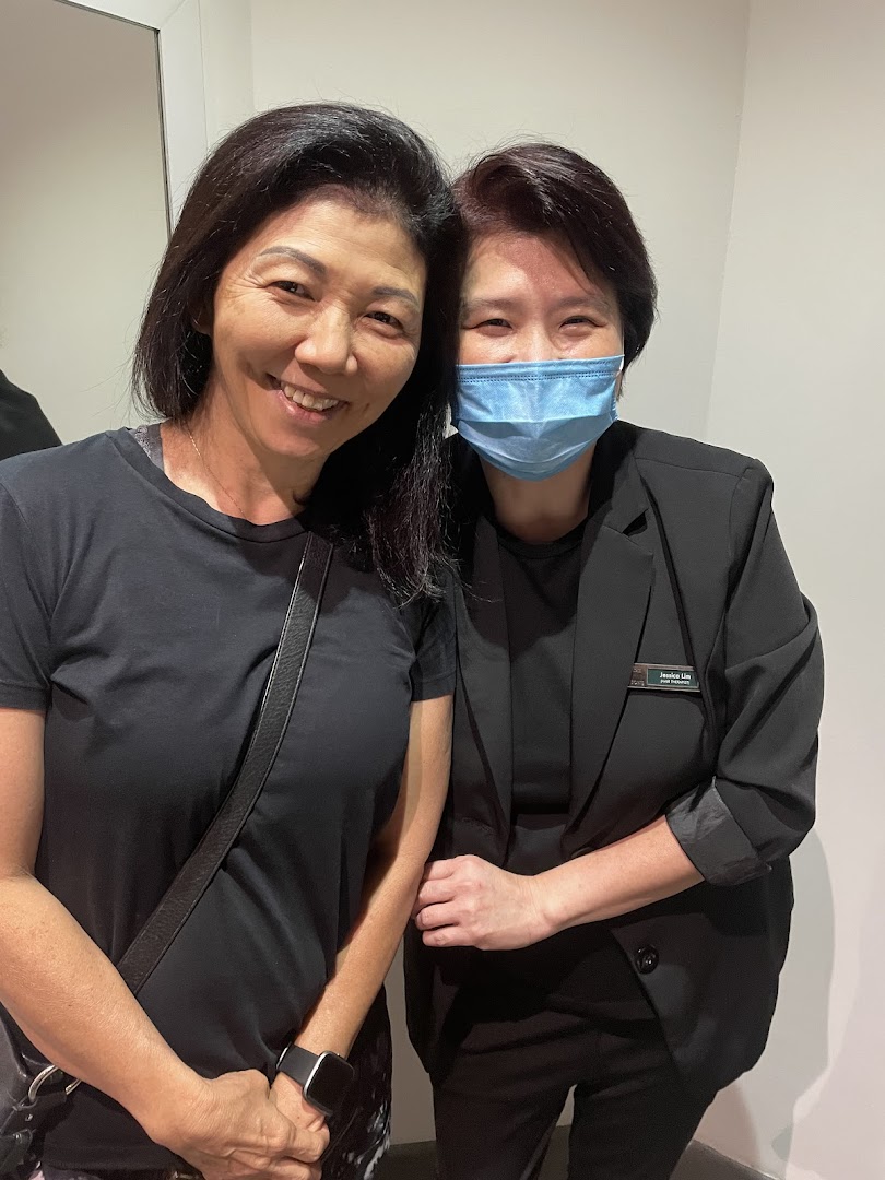 Two women, one a staff member, smiling warmly inside Oriental Hair Solutions.