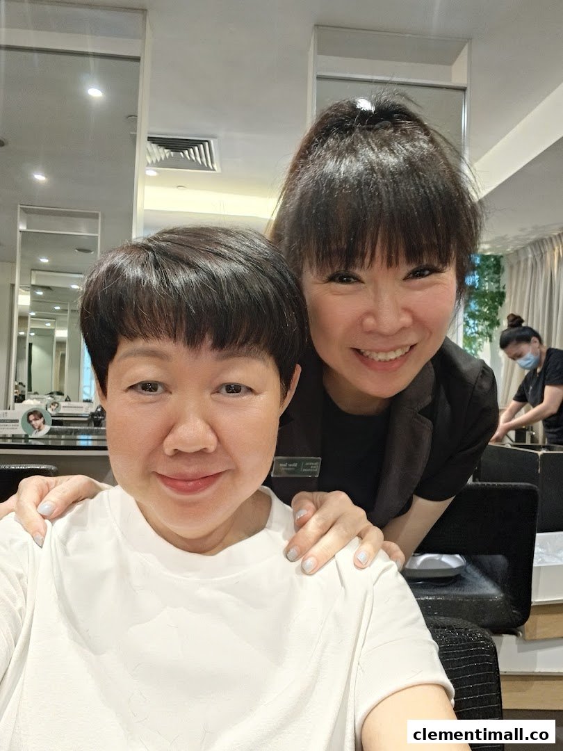 Two smiling women, a customer and a stylist, in a modern hair salon setting.
