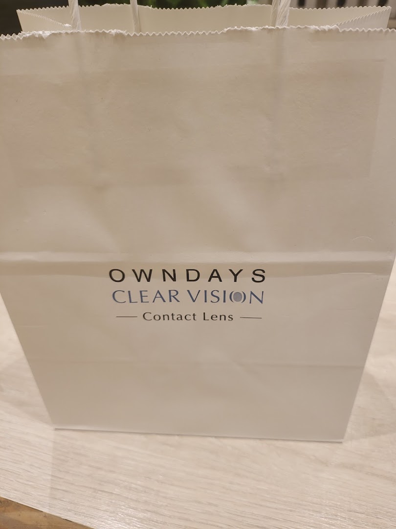 A white OWNDAYS shopping bag featuring 'CLEAR VISION Contact Lens' branding.