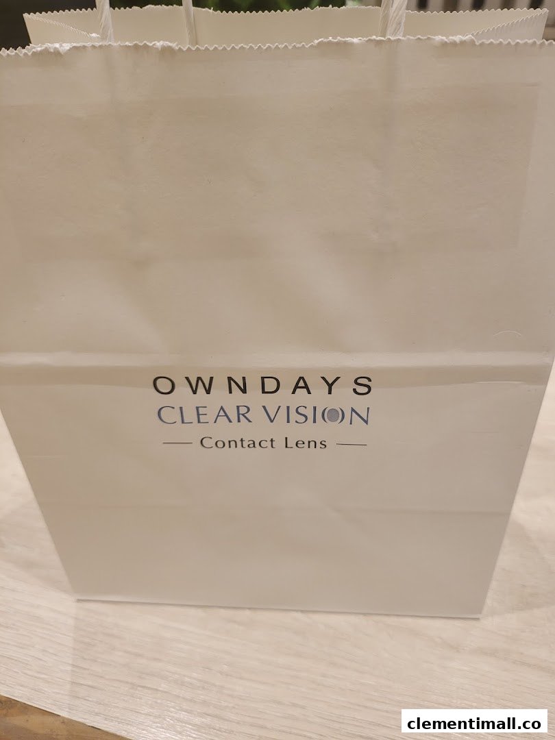 A white OWNDAYS shopping bag featuring 'CLEAR VISION Contact Lens' branding.