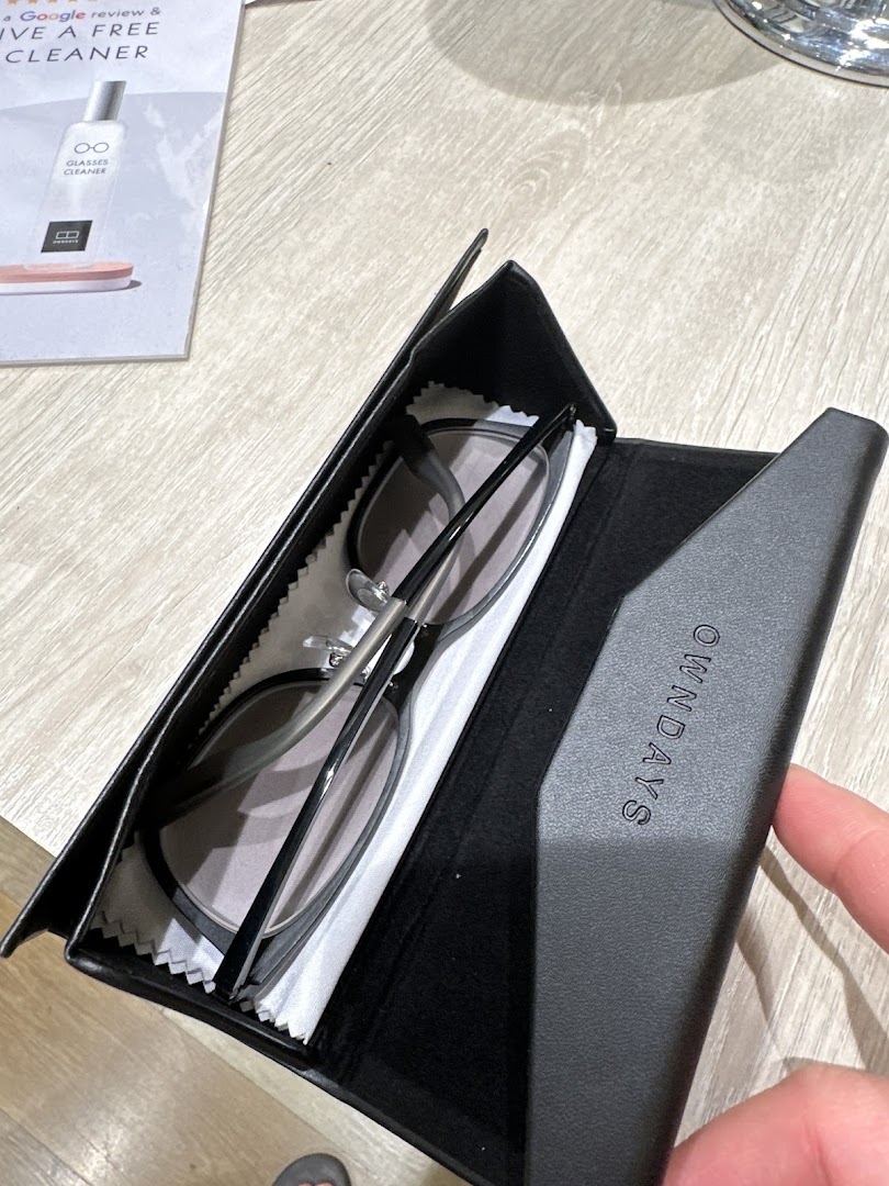 A pair of stylish glasses resting in an OWNDAYS branded case on a wooden surface.
