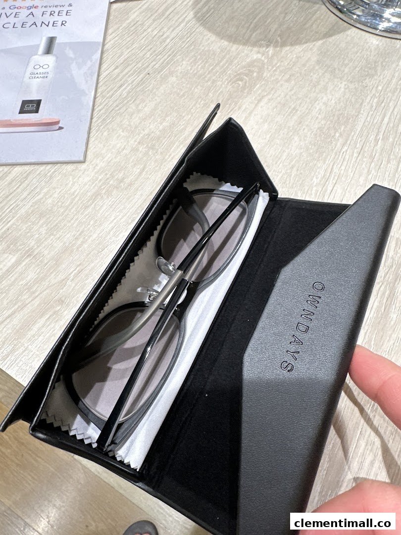 A pair of stylish glasses resting in an OWNDAYS branded case on a wooden surface.