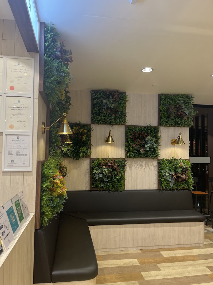 A comfortable seating area with modern green wall decor and warm lighting inside OWNDAYS.