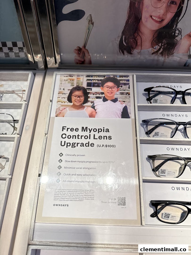 A display at OWNDAYS featuring a promotional sign for free myopia control lens upgrade and various eyewear frames.
