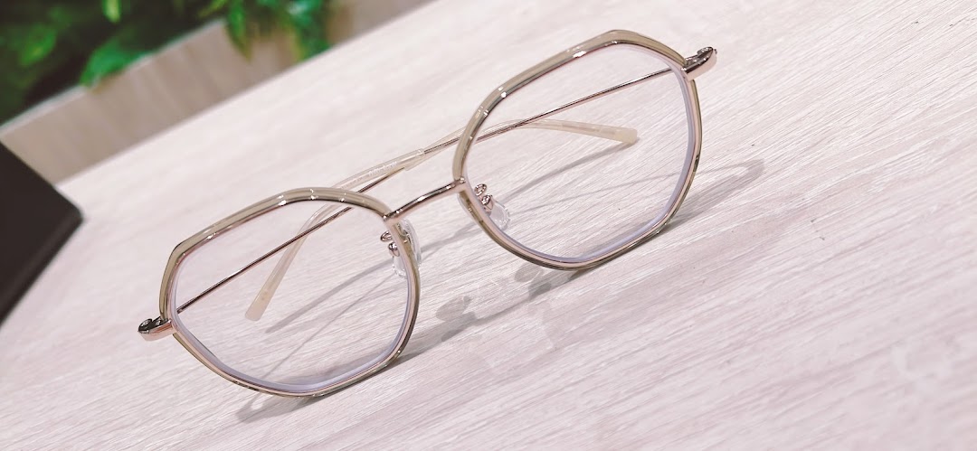 A stylish pair of modern eyeglasses with a light-colored frame rests on a wooden surface.
