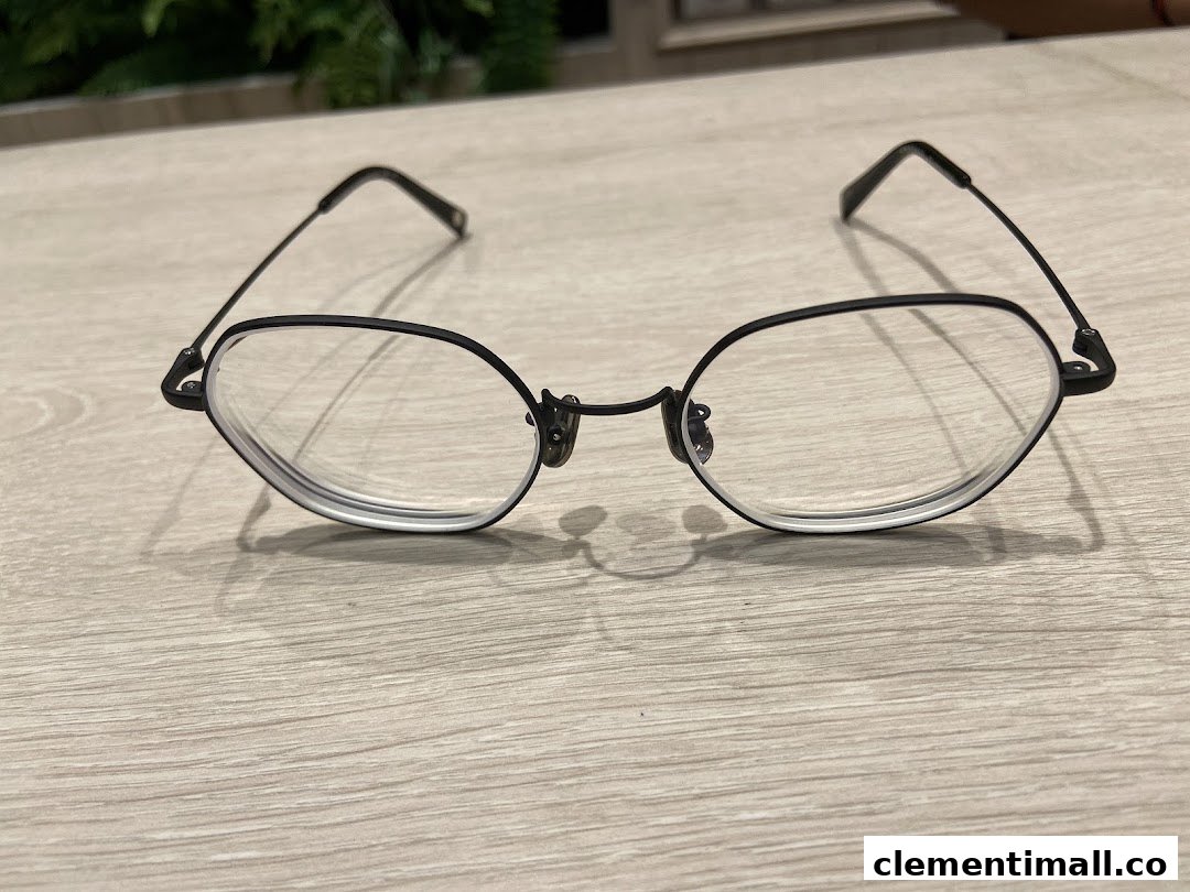 A stylish pair of black-framed eyeglasses rests on a light wooden surface.