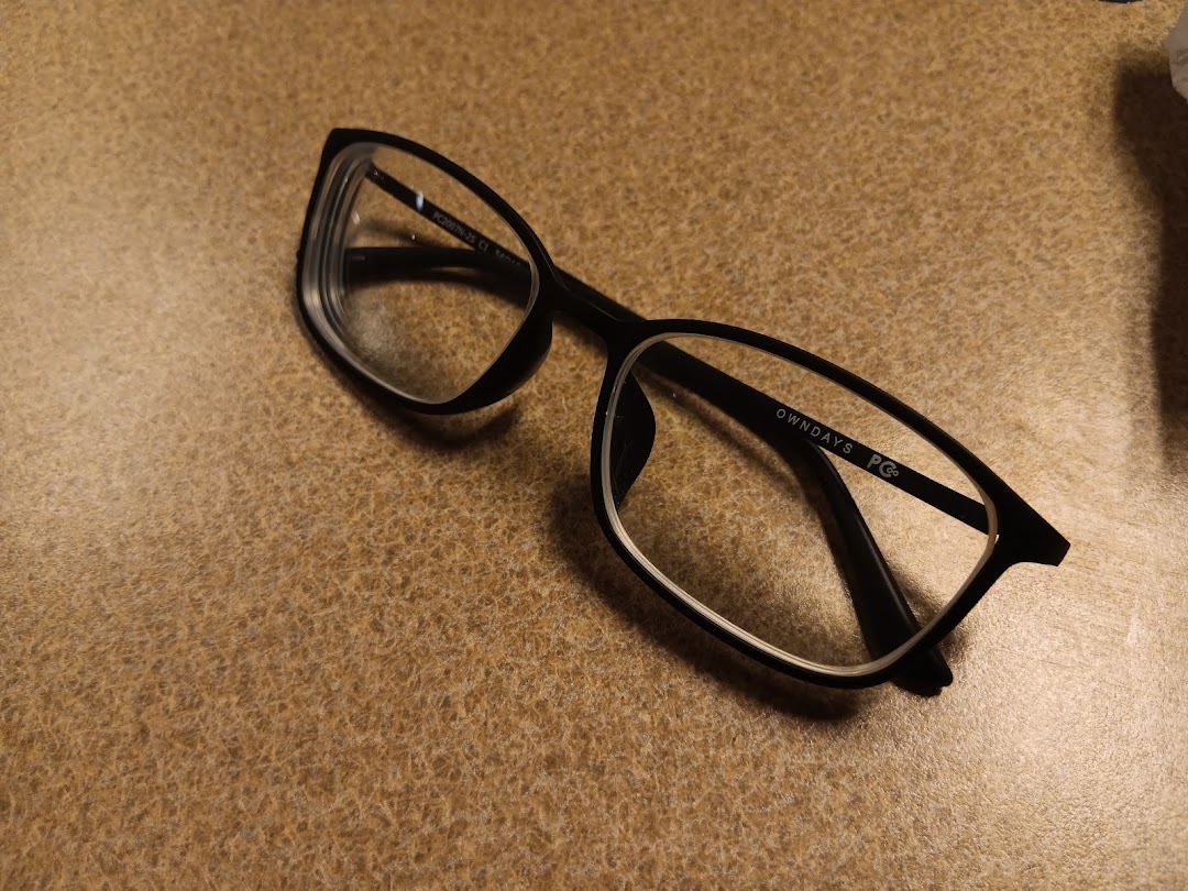 A stylish pair of black OWNDAYS eyeglasses rests on a textured brown surface.