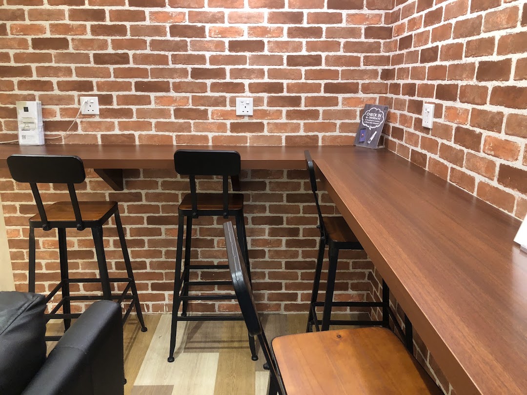A comfortable waiting area with charging stations and high stools against a brick wall.