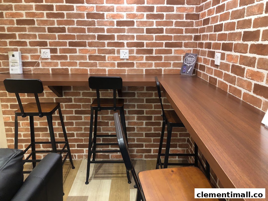 A comfortable waiting area with charging stations and high stools against a brick wall.