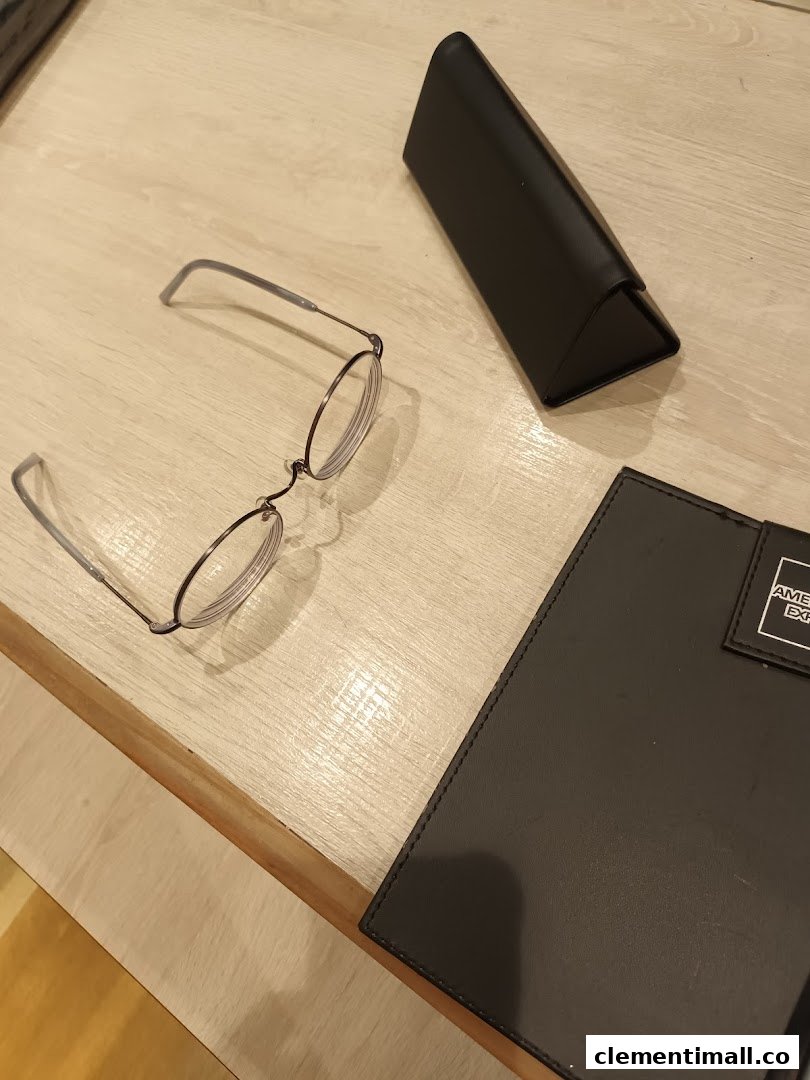 A pair of stylish round eyeglasses and a case on a light wooden surface.