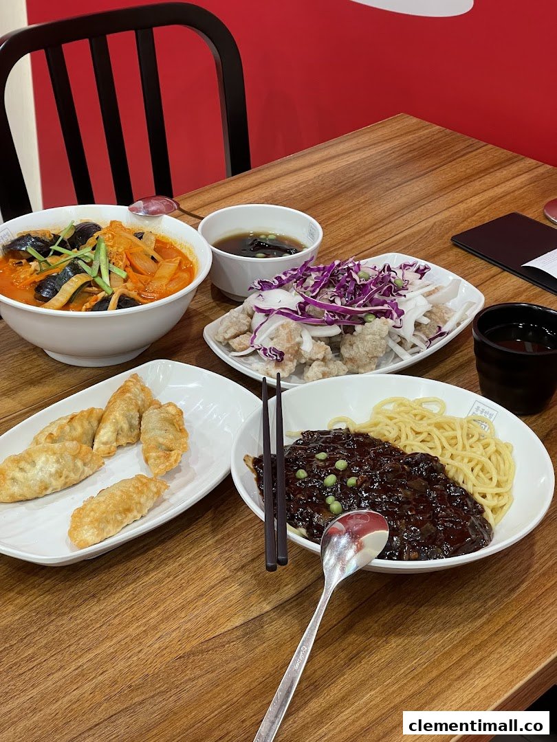 A table laden with various Korean dishes including Jajangmyeon, Jjamppong, fried dumplings, and sweet and sour chicken.