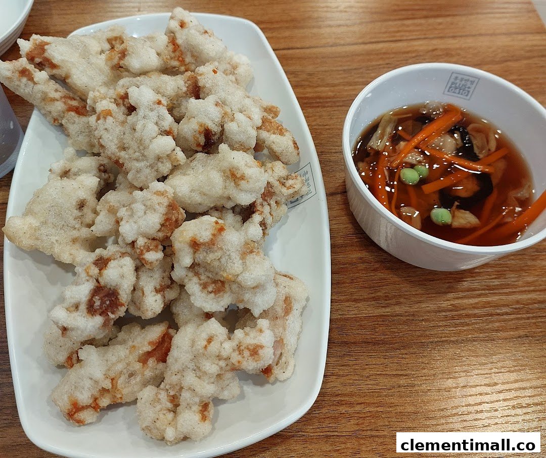 A plate of crispy fried meat (likely Tangsuyuk) served with a sweet and sour dipping sauce.
