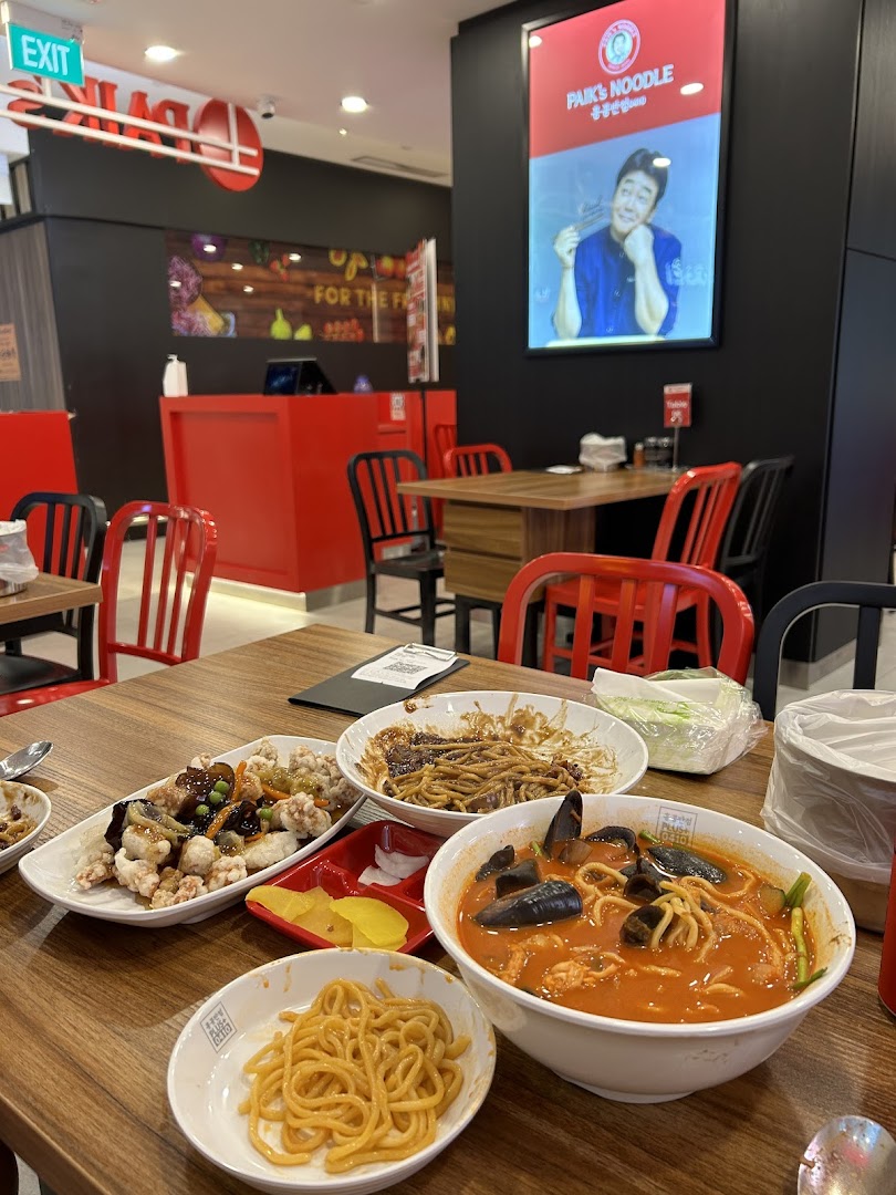 A table laden with various Korean noodle dishes and side dishes inside Paik's Noodle restaurant.