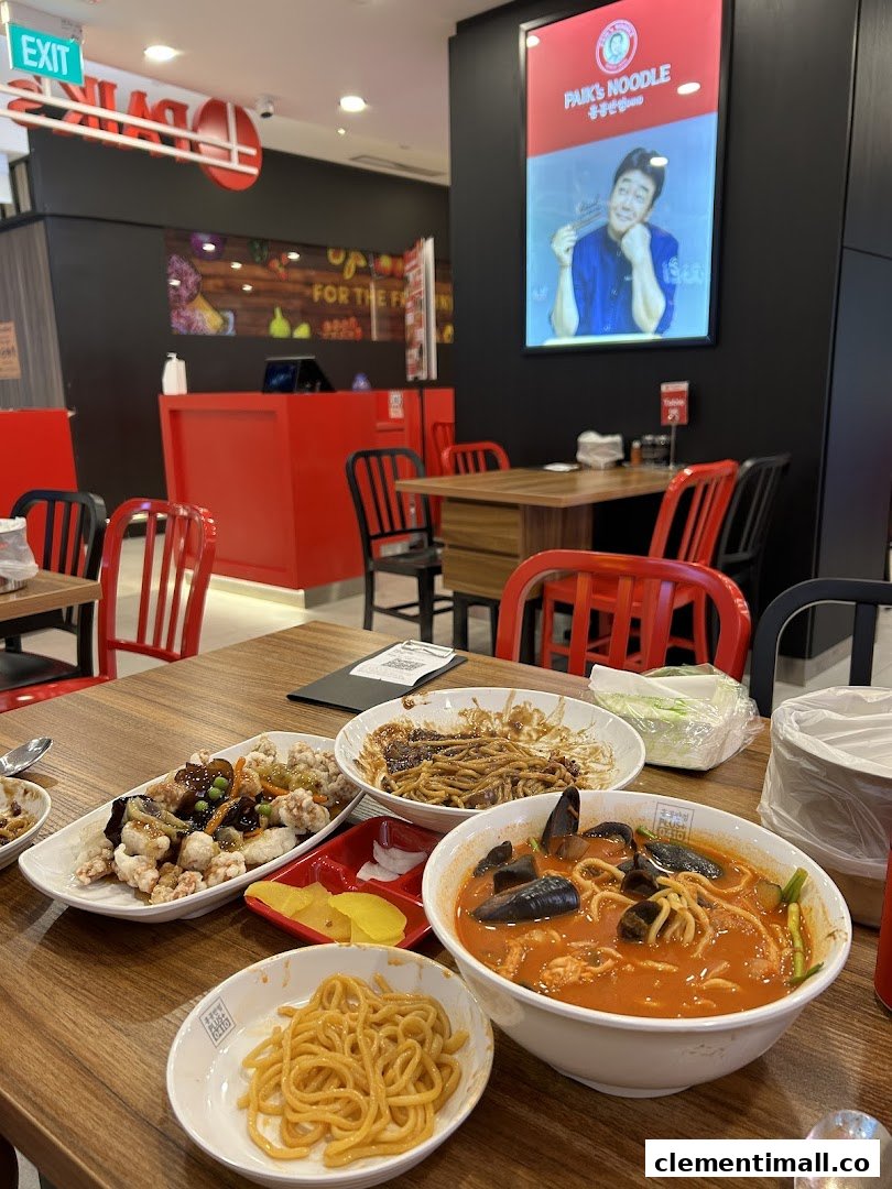 A table laden with various Korean noodle dishes and side dishes inside Paik's Noodle restaurant.