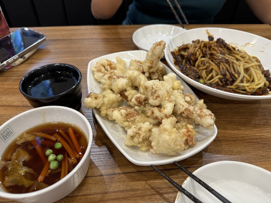 A table laden with delicious Korean-Chinese dishes, including Jajangmyeon, Tangsuyuk, and a side soup.