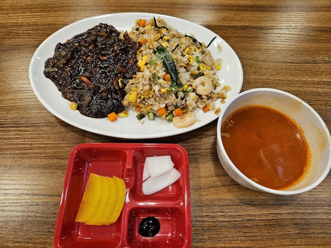 A Korean-Chinese combo meal featuring black bean sauce, shrimp fried rice, and side dishes.