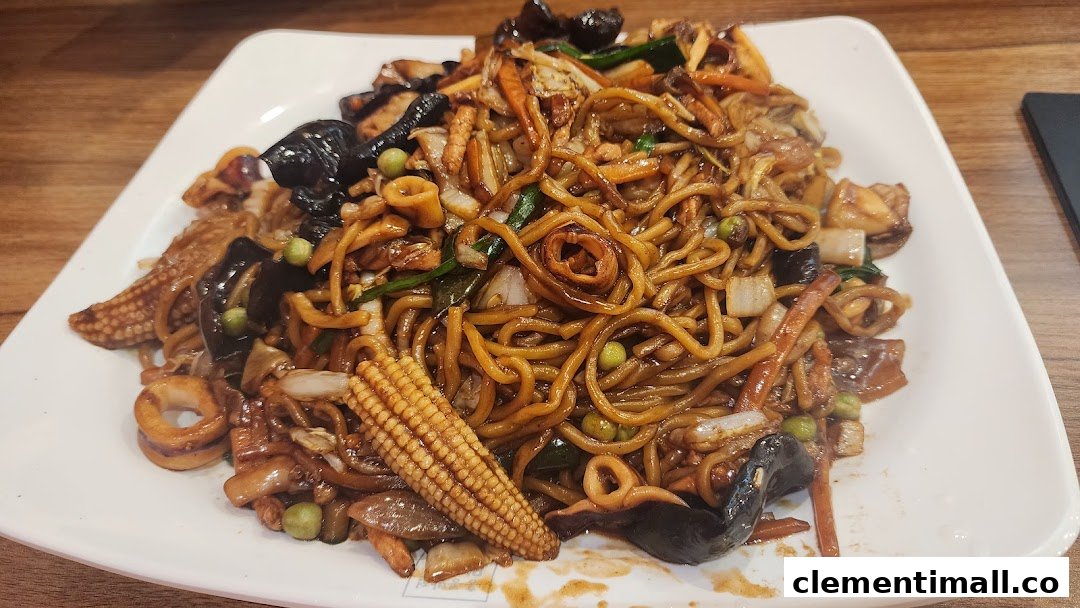 A close-up of a delicious plate of stir-fried noodles with vegetables, baby corn, and seafood.
