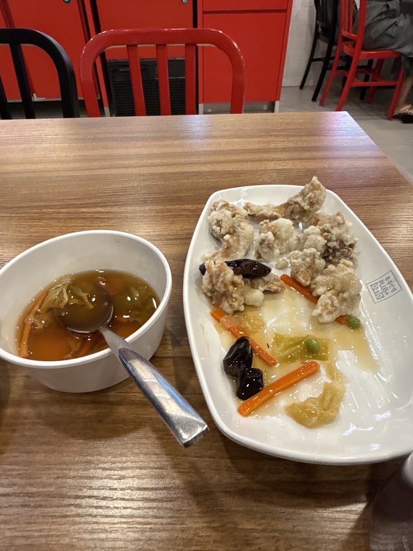 A close-up of a meal featuring fried chicken and a bowl of soup on a wooden table.