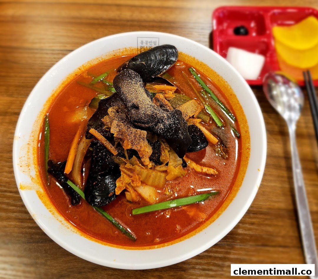 A vibrant bowl of spicy seafood noodles with mussels and vegetables, served with side dishes.
