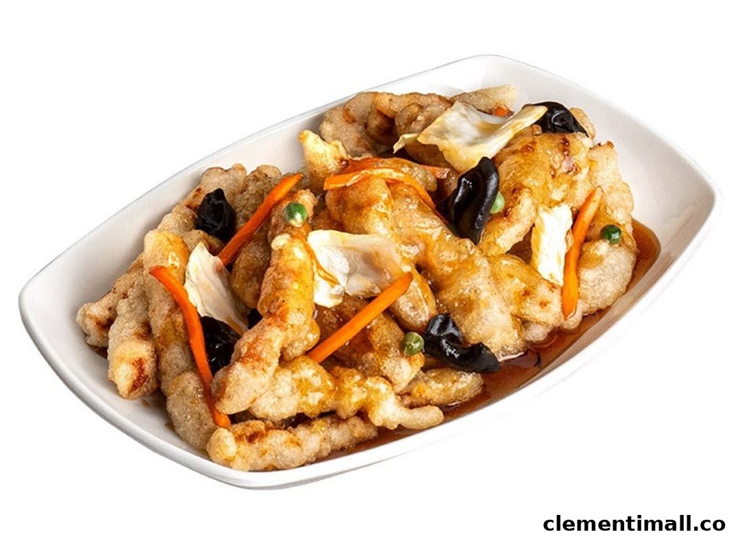 A white rectangular dish filled with golden-brown fried meat, carrots, wood ear mushrooms, and cabbage in a sauce.