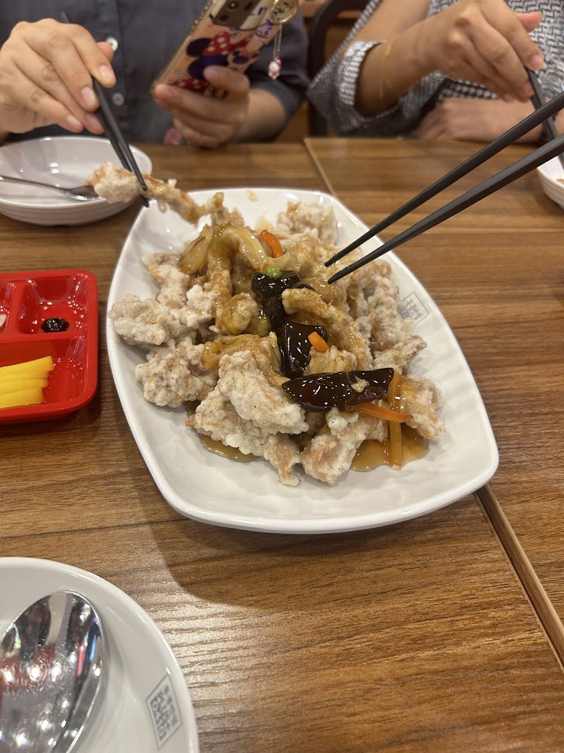 Diners enjoy a plate of crispy fried meat with sauce, showcasing a popular dish.