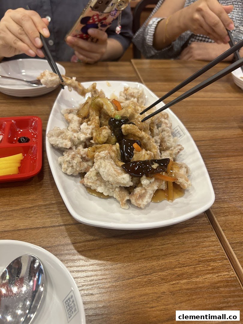 Diners enjoy a plate of crispy fried meat with sauce, showcasing a popular dish.