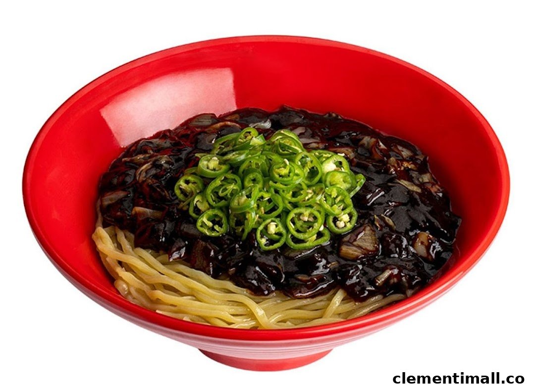 A vibrant red bowl filled with Jajangmyeon noodles, topped with rich black bean sauce and fresh green chili slices.