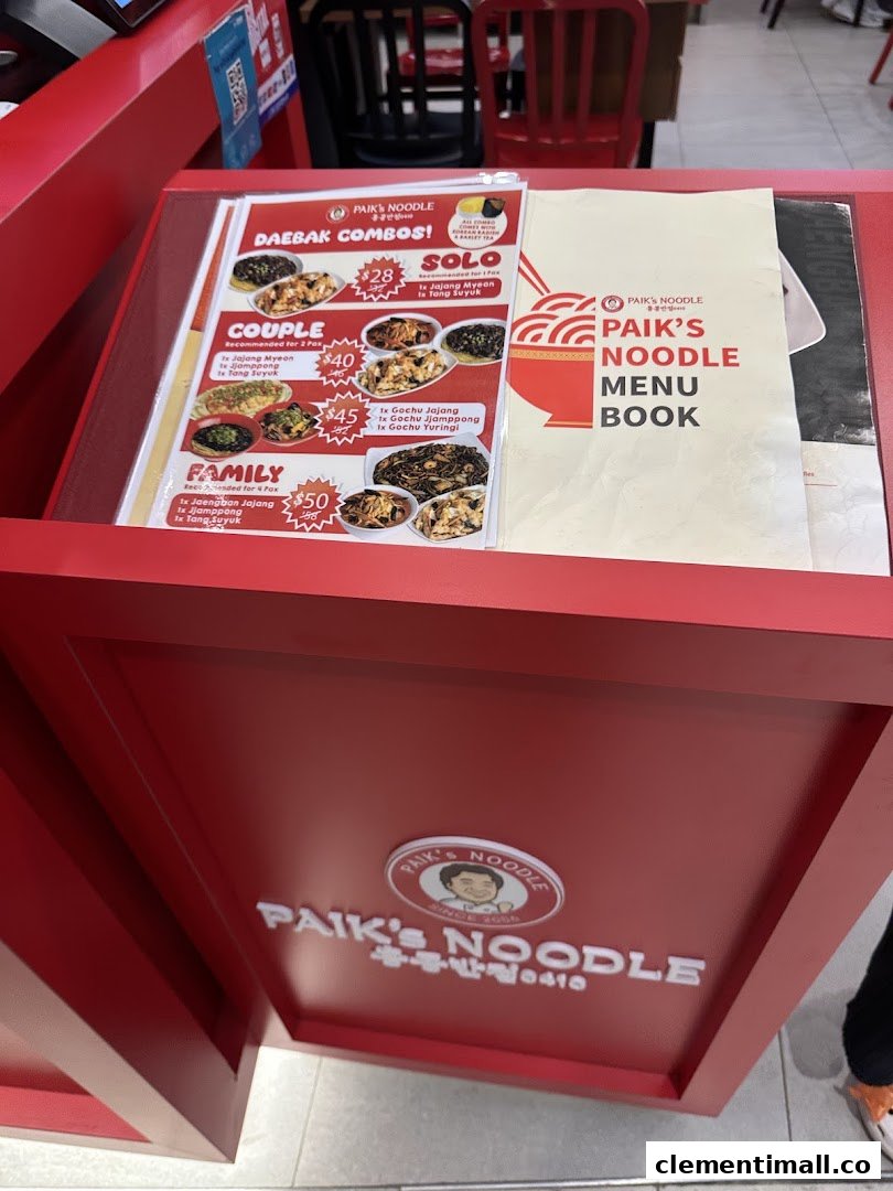A red menu stand displaying Paik's Noodle 'Daebak Combos' and a menu book.