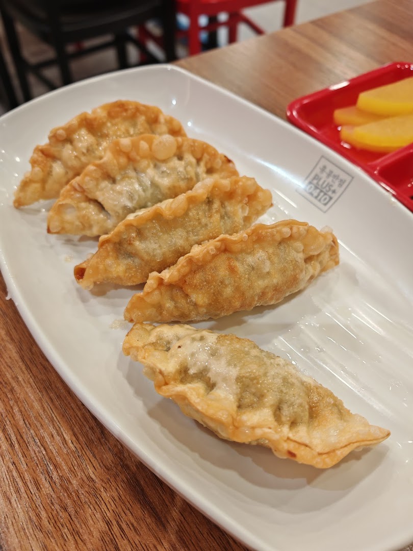 A plate of golden-fried Korean dumplings (mandu) served with pickled radish.