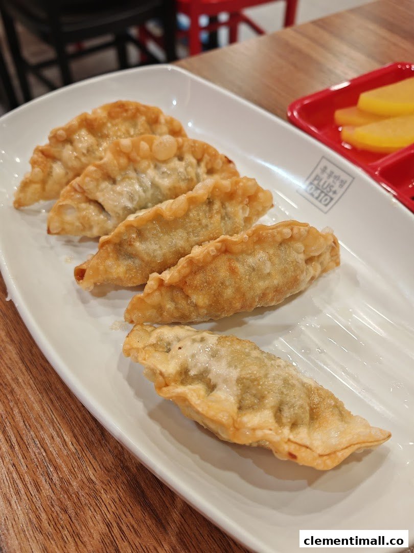A plate of golden-fried Korean dumplings (mandu) served with pickled radish.