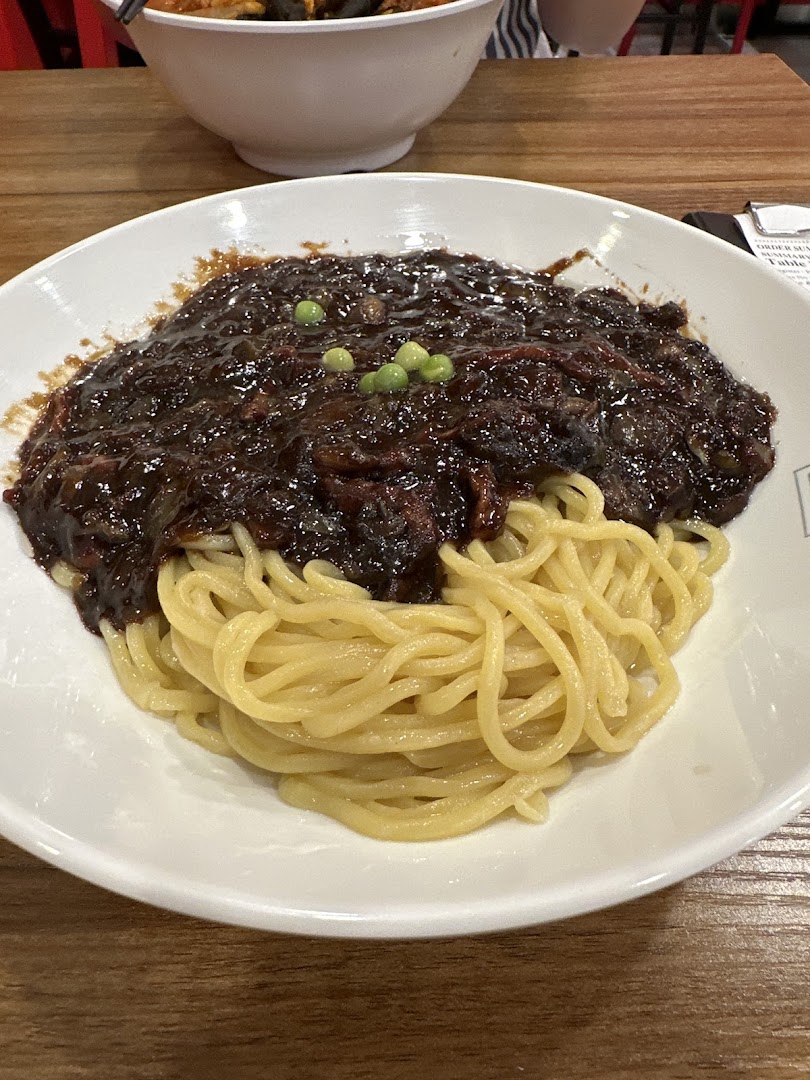 A close-up of a delicious bowl of Jajangmyeon with black bean sauce and noodles.