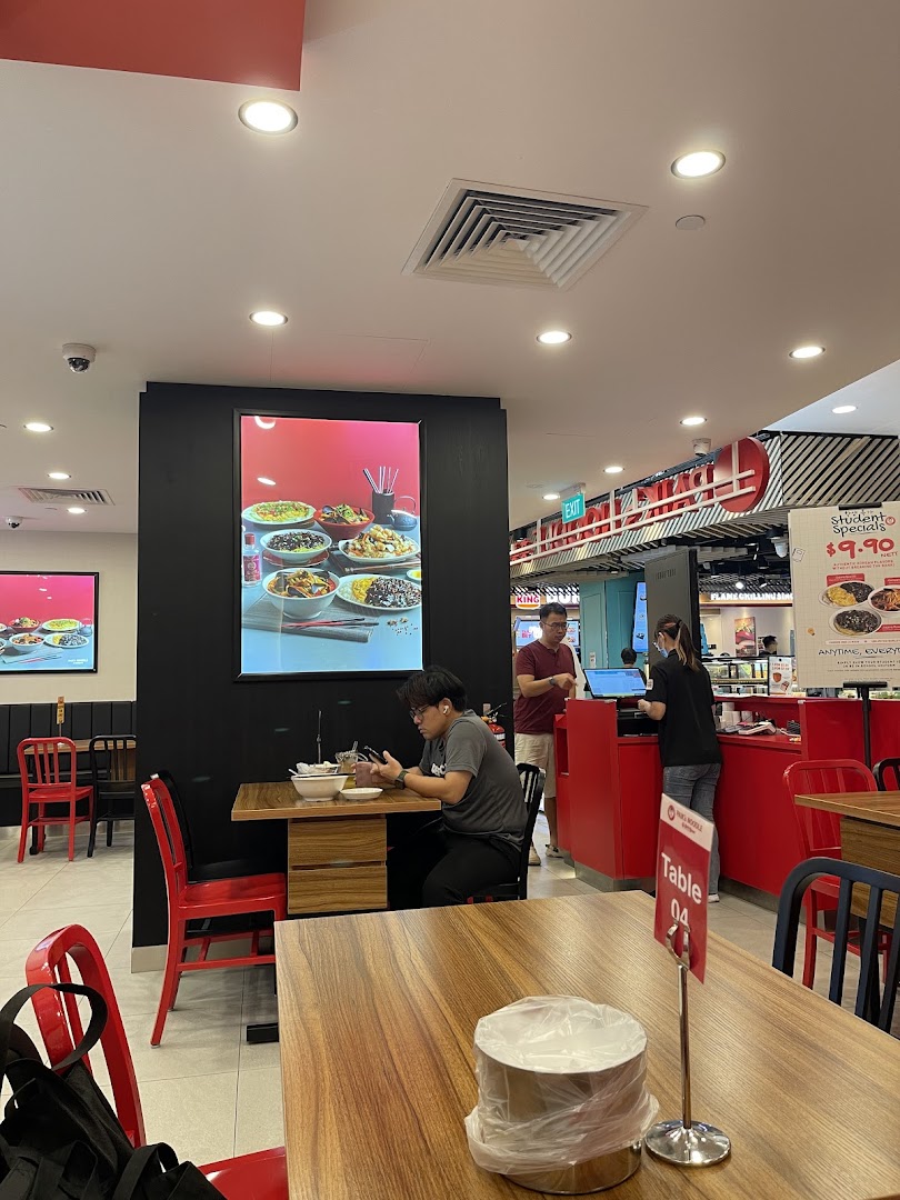 Interior view of Paiks Noodle showing customers dining and a vibrant red counter area.