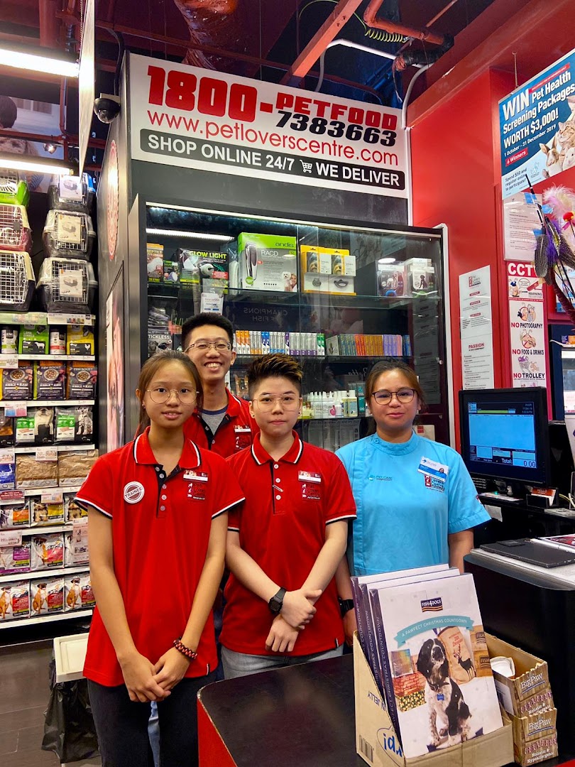 Four friendly staff members stand at the counter of Pet Lovers Centre, surrounded by pet products.