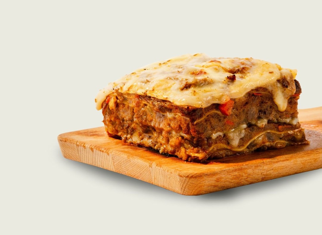 A delicious, cheesy lasagna slice served on a wooden cutting board.