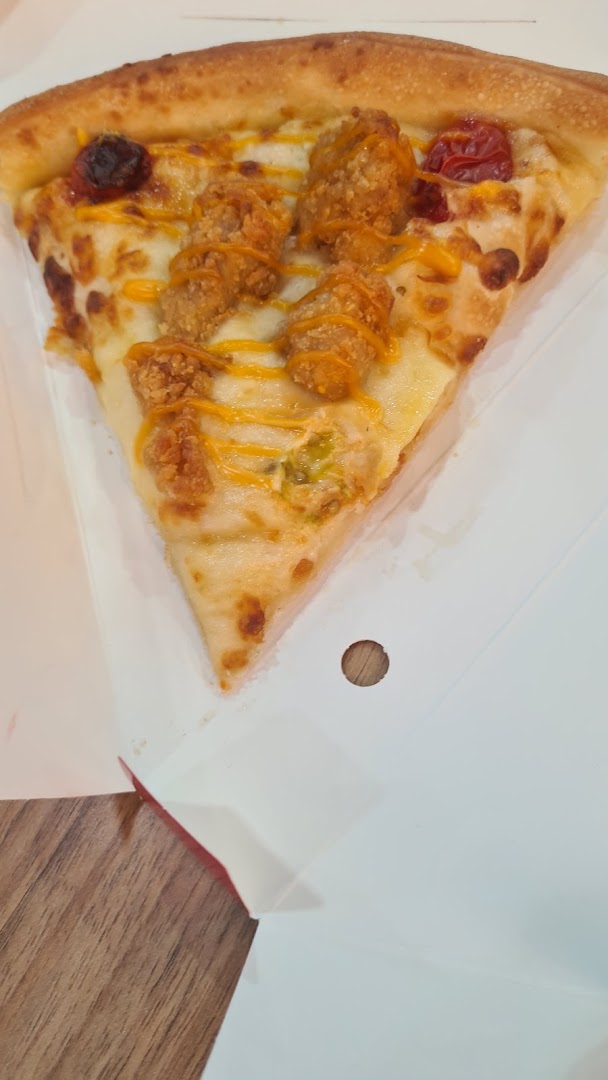 A close-up of a delicious pizza slice topped with crispy chicken pieces, cheese, and sauce.