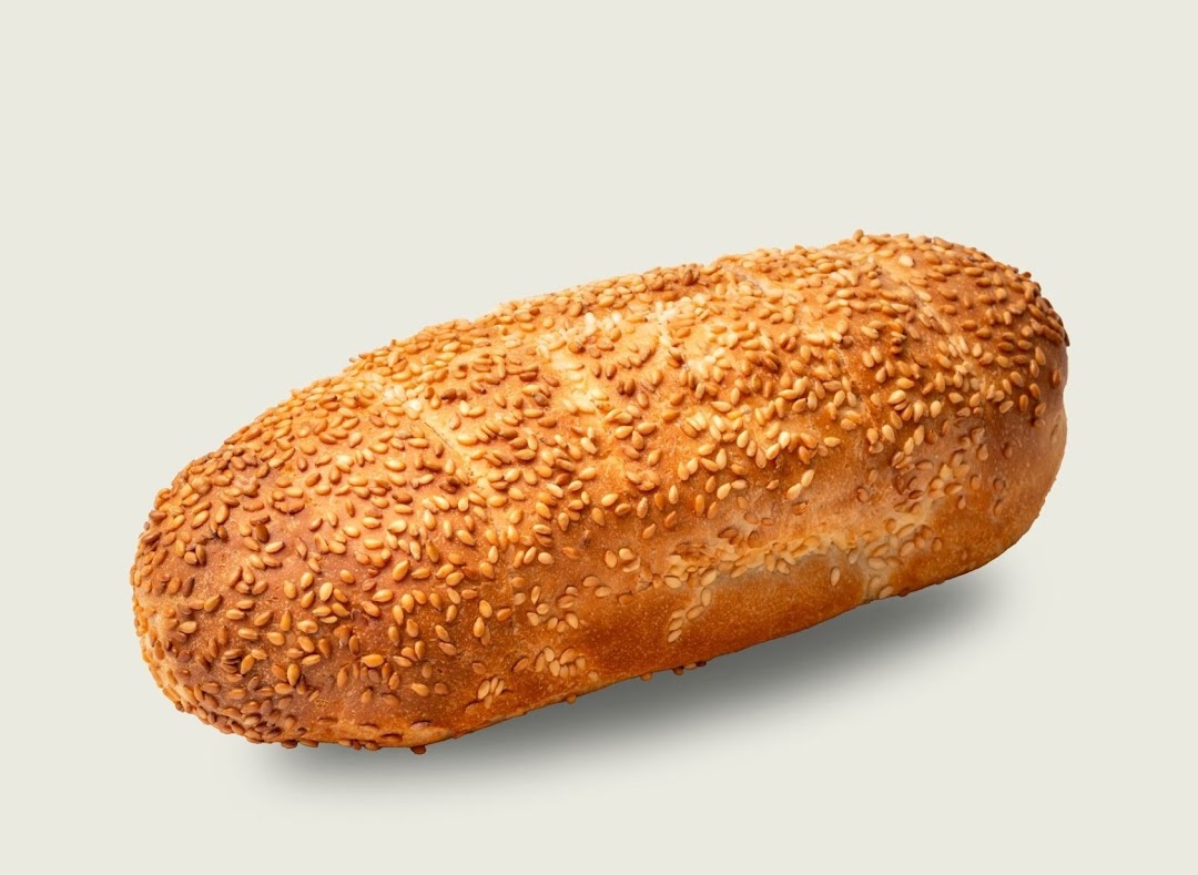 A close-up of a golden-brown bread loaf generously covered with toasted sesame seeds.