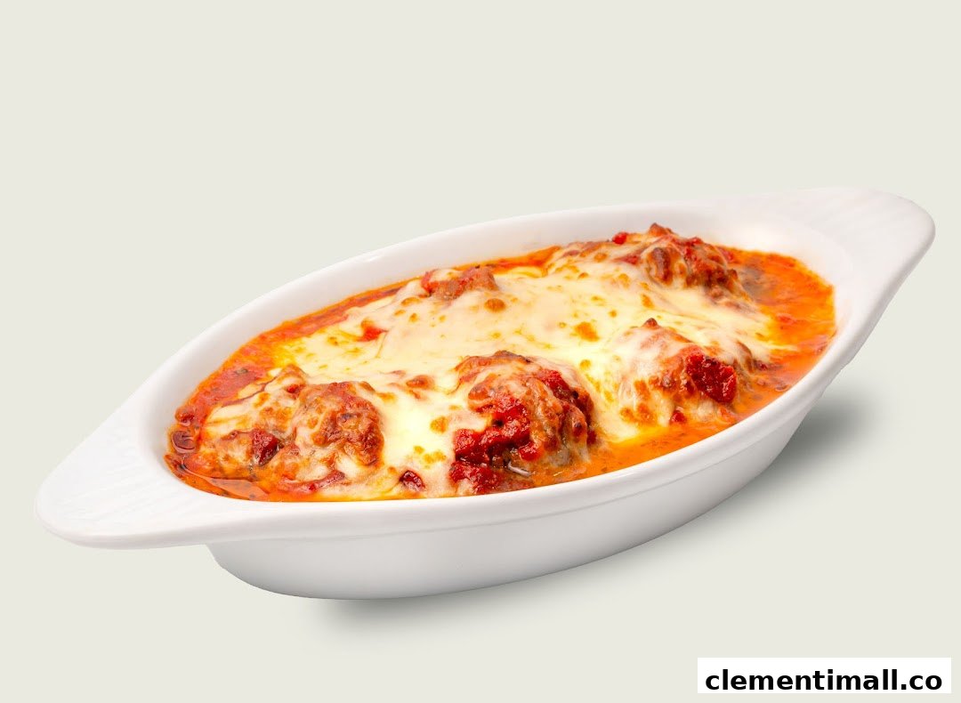 A white baking dish filled with cheesy meatballs in rich tomato sauce.