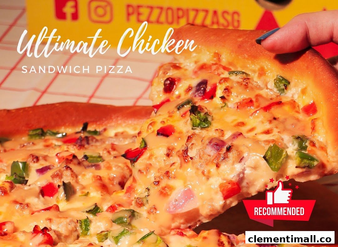 A hand holds a delicious slice of Pezzo's Ultimate Chicken Sandwich Pizza, showcasing melted cheese and vibrant toppings.