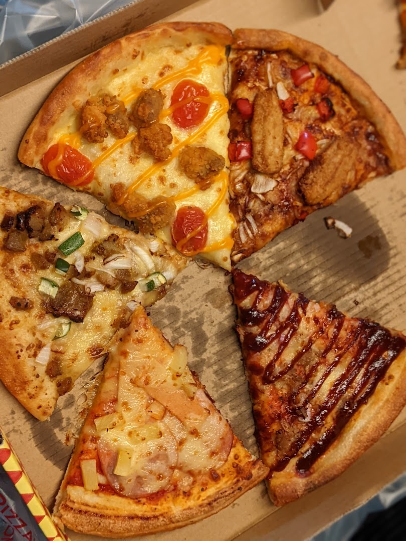 A close-up view of various delicious pizza slices with different toppings in a box.