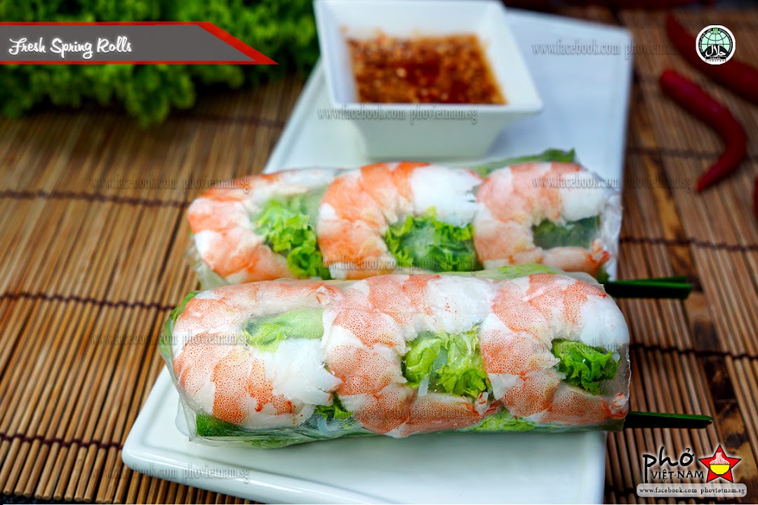 Two fresh Vietnamese spring rolls filled with shrimp and lettuce, served with a dipping sauce.