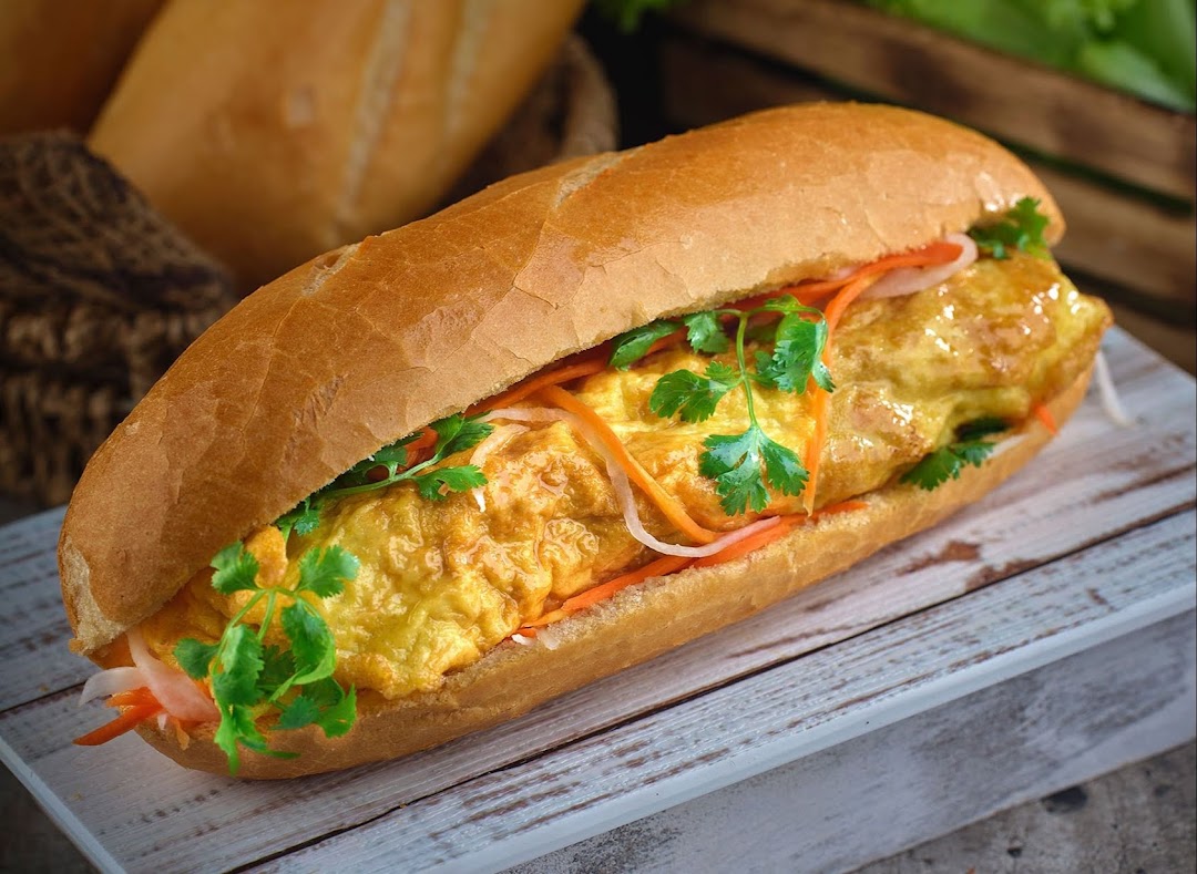 A close-up of a delicious Vietnamese Banh Mi sandwich with omelette and fresh herbs.