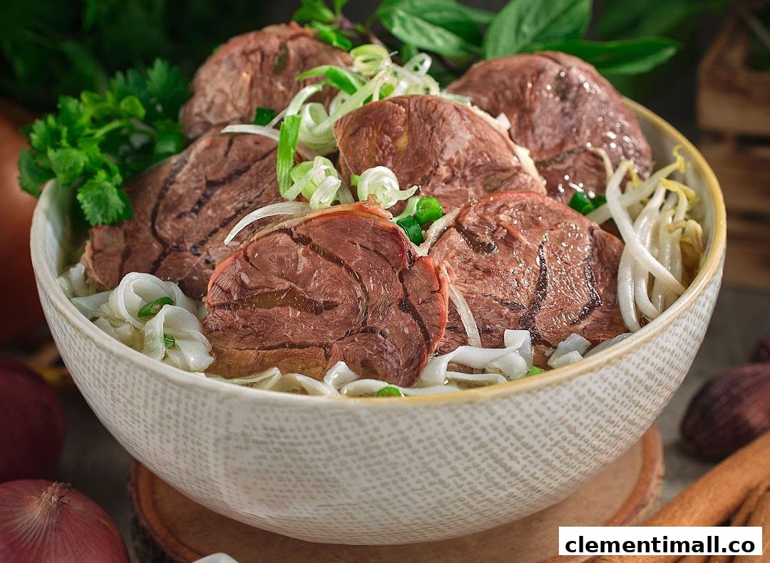 A close-up of a delicious bowl of Vietnamese pho with sliced beef, noodles, and fresh herbs.