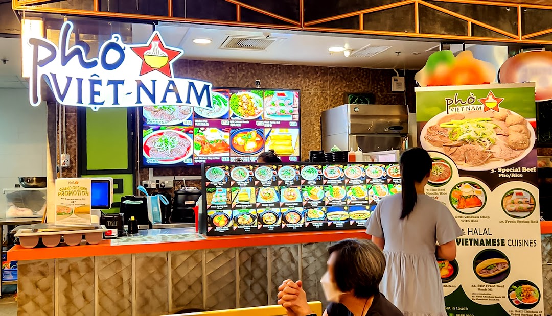 A vibrant Pho Vietnam food stall with digital menus and customers at the counter.