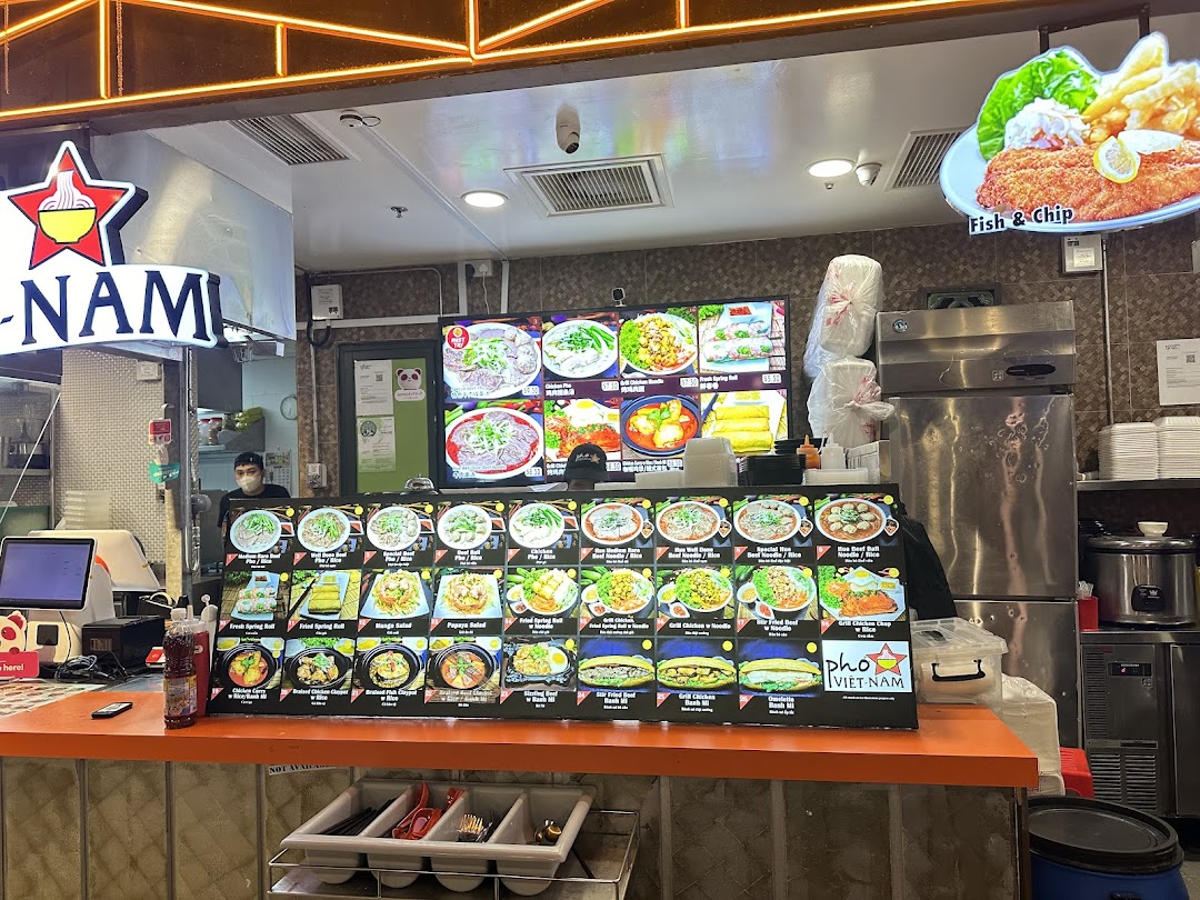 A vibrant food stall counter displaying various Vietnamese dishes and a digital menu.