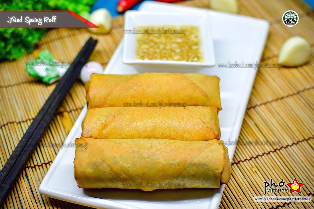 Golden fried spring rolls served with a savory dipping sauce on a bamboo mat.