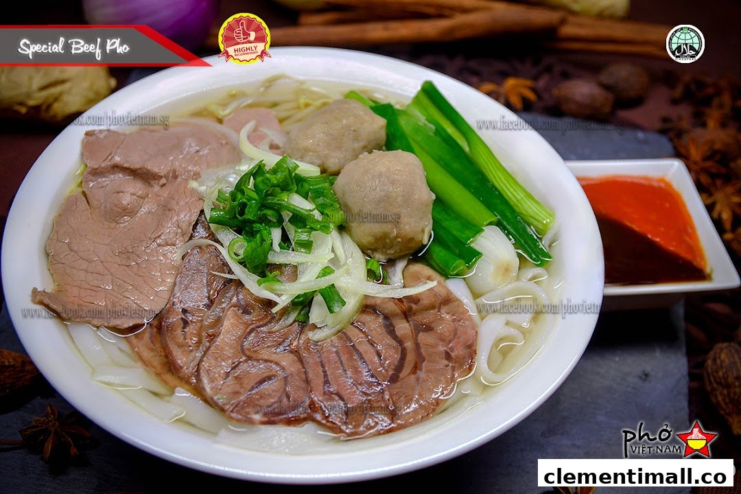 A close-up of a Special Beef Pho bowl with beef slices, meatballs, and fresh herbs.