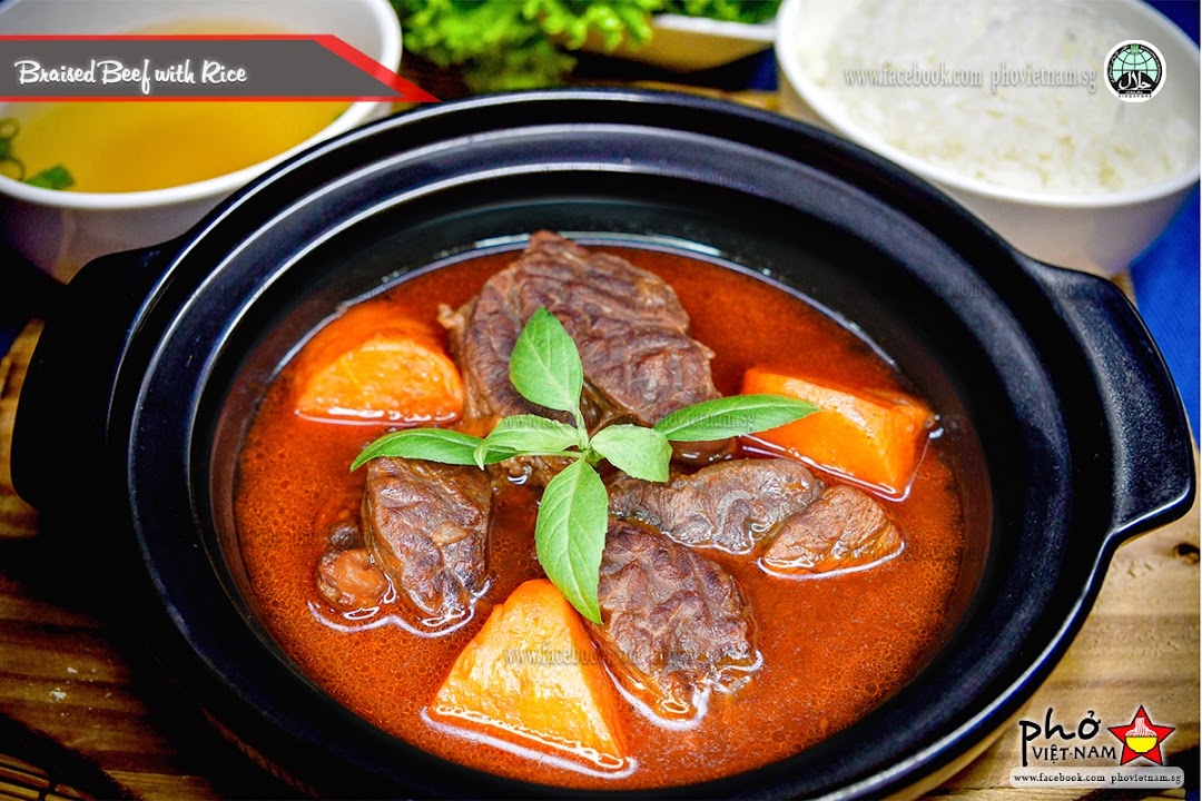 A hearty pot of braised beef with carrots and basil, served with rice and a side of soup.