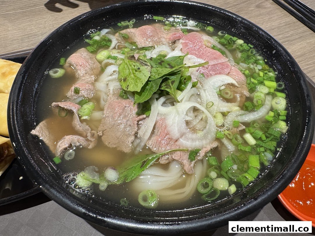A close-up of a delicious bowl of Vietnamese pho with beef, noodles, and fresh herbs.