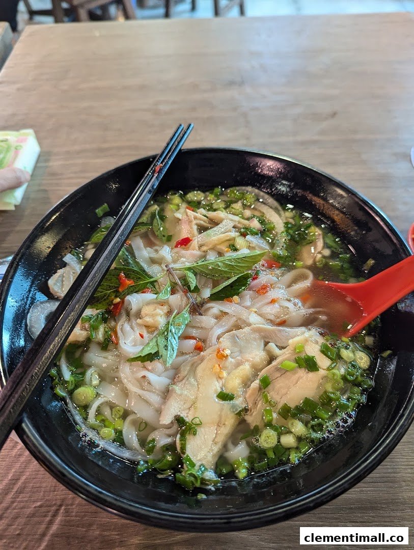 A close-up of a delicious bowl of chicken pho with fresh herbs and noodles.