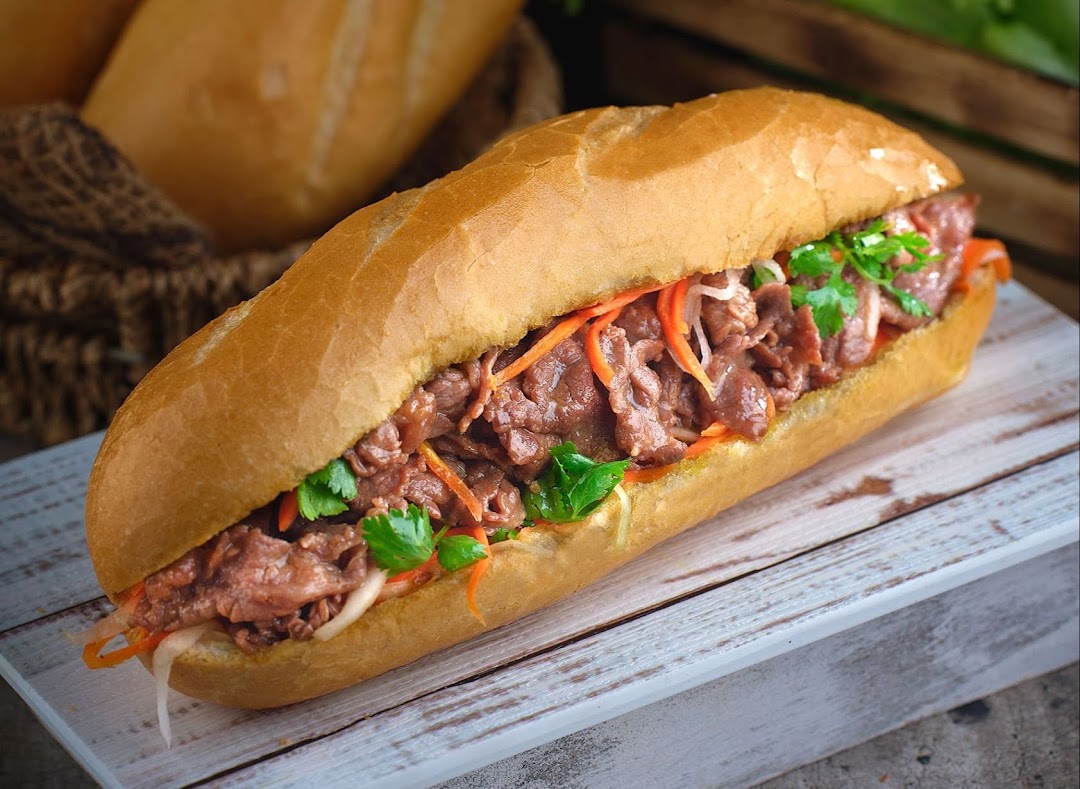 A close-up of a delicious Vietnamese Banh Mi sandwich filled with beef and fresh vegetables.